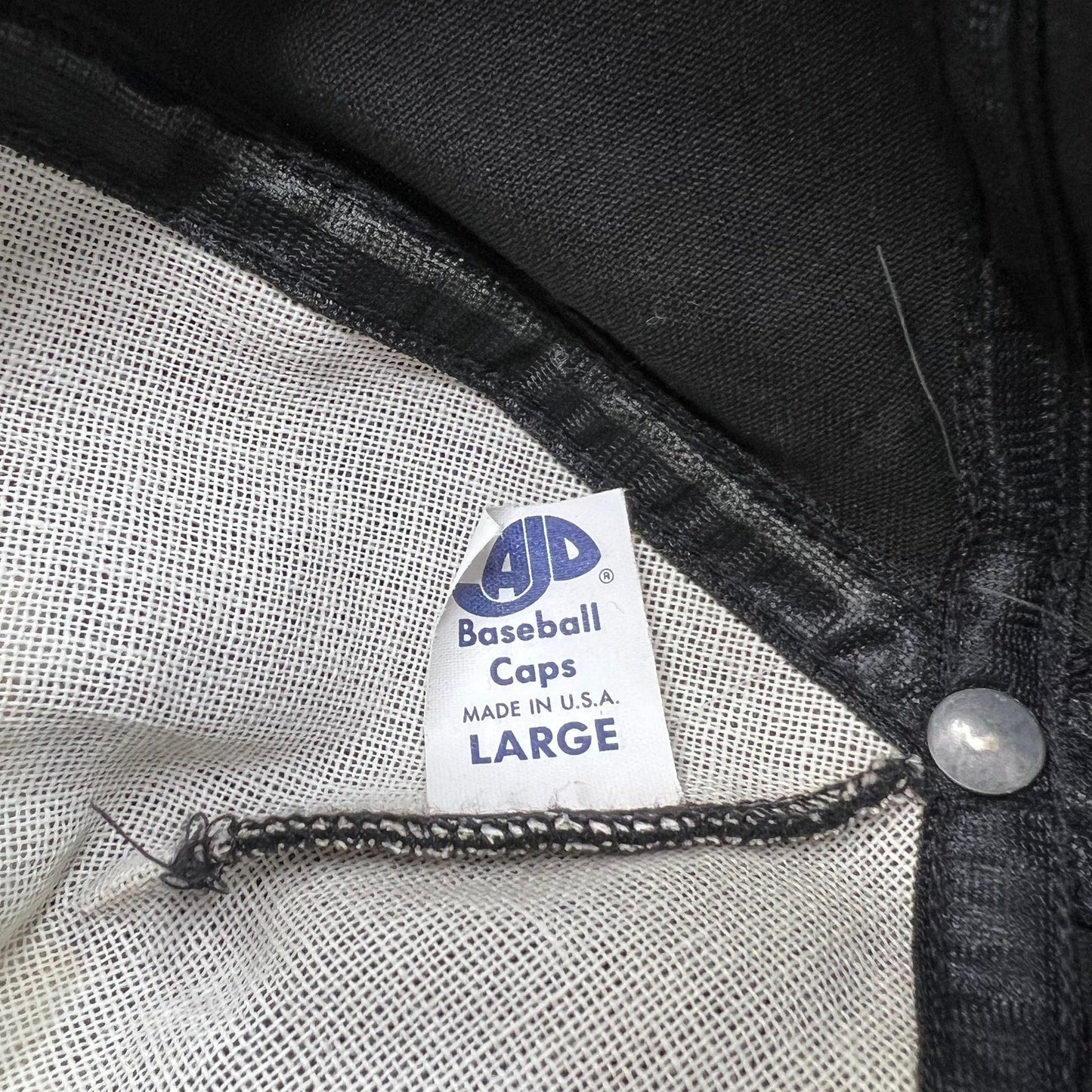 Raree Finds vintage AJD Baseball Caps tag inside a black snapback hat made in the USA