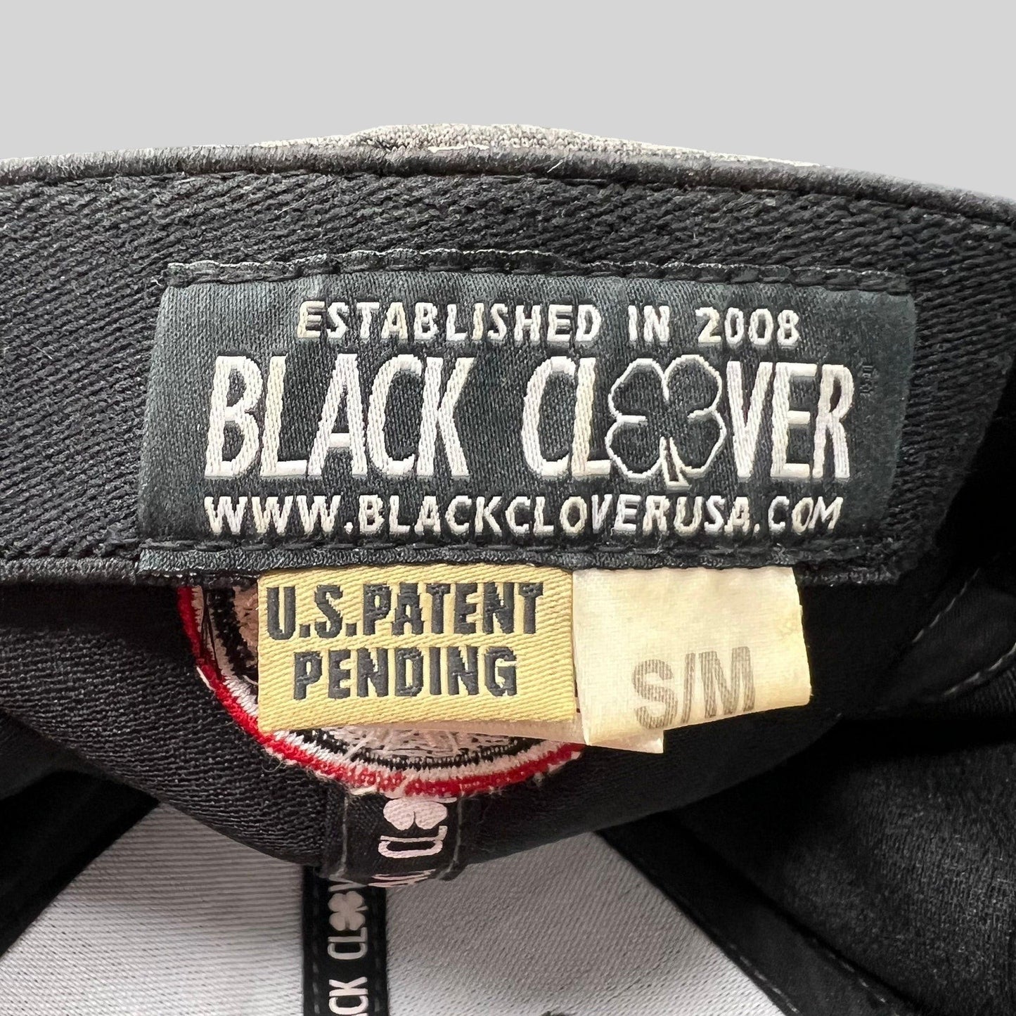 Raree Finds Black Clover cap interior label showing brand logo, patent pending status, and size S/M tag