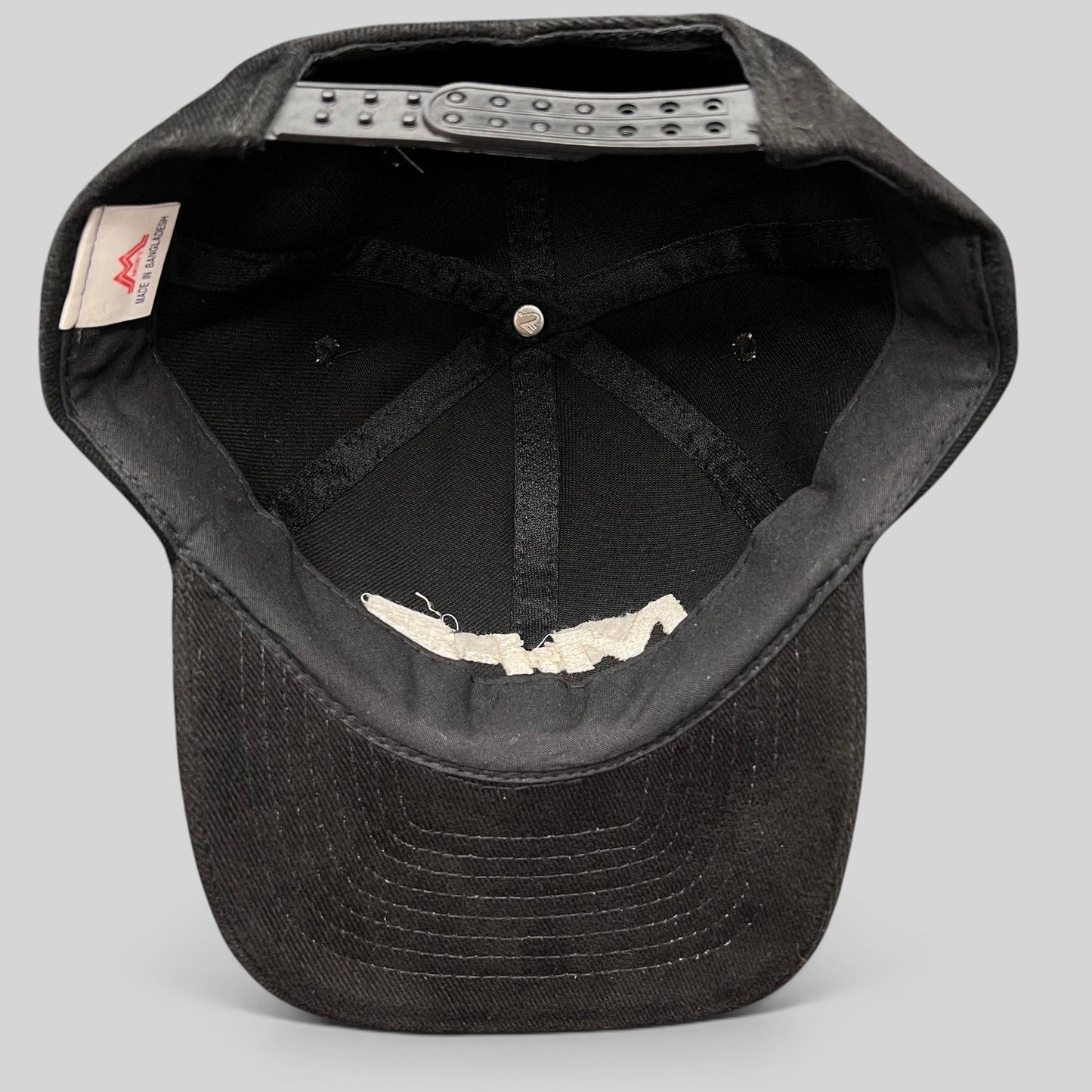 Interior view of a black Raree Finds vintage Mission Impossible 2 corduroy snapback hat showing the adjustable strap.