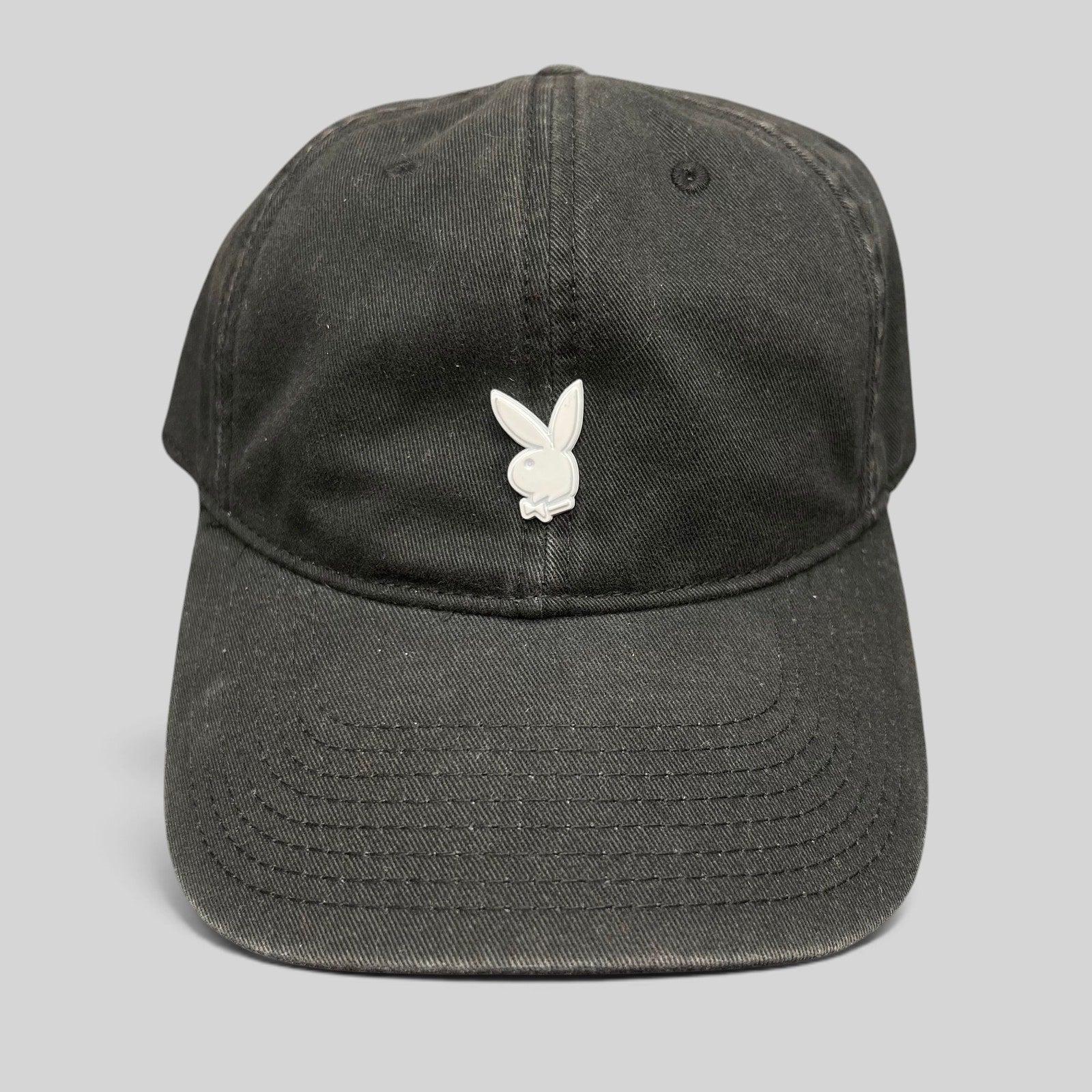 Raree Finds black strapback hat featuring a minimalist silver metal Playboy bunny logo on the front crown.