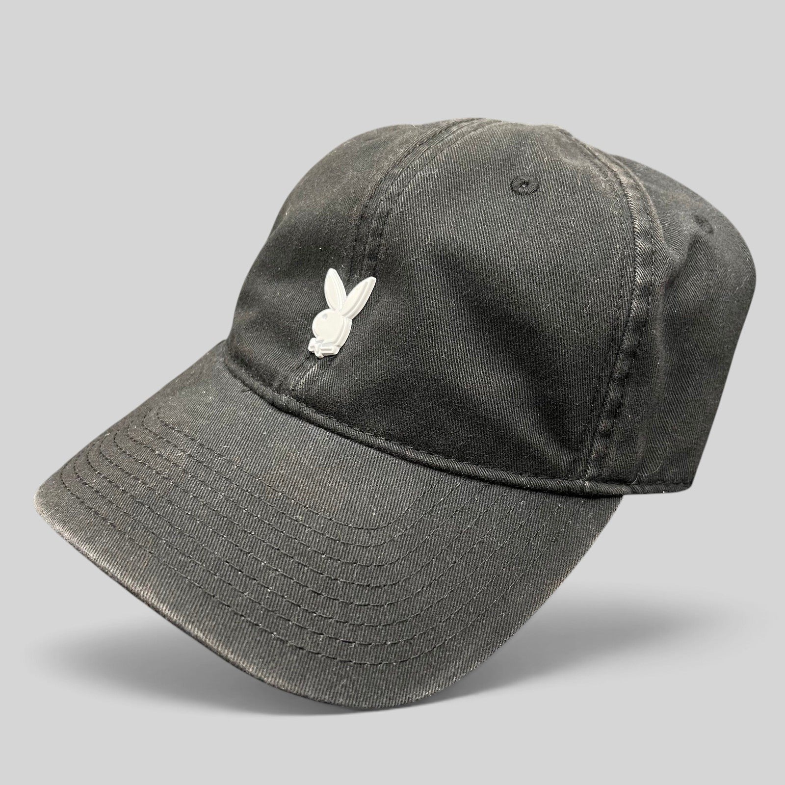 Raree Finds black cotton strapback hat featuring a minimalist raised metal Playboy bunny logo on the front crown.