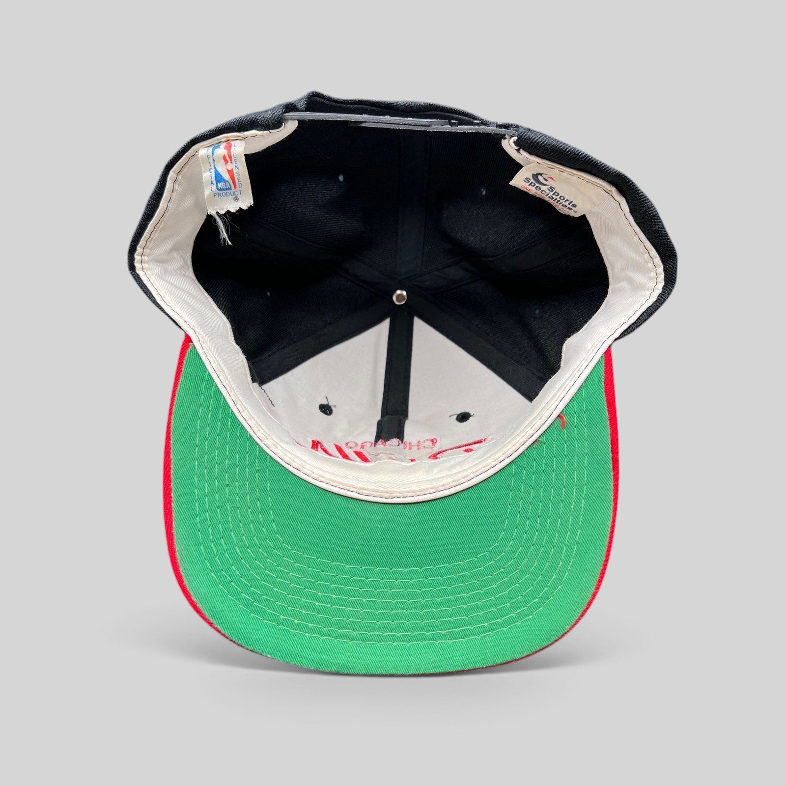 Raree Finds vintage 90s Chicago Bulls snapback hat showing the interior green undervisor and original brand tags.
