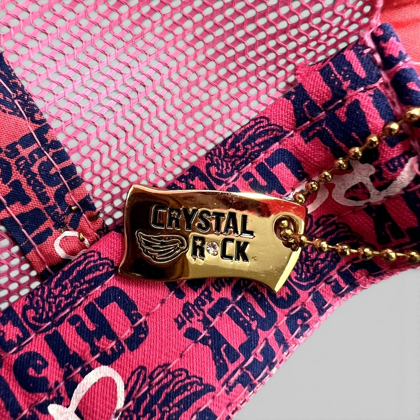 Raree Finds Crystal Rock by Christian Audigier pink trucker hat featuring a gold branded metal tag with rhinestones