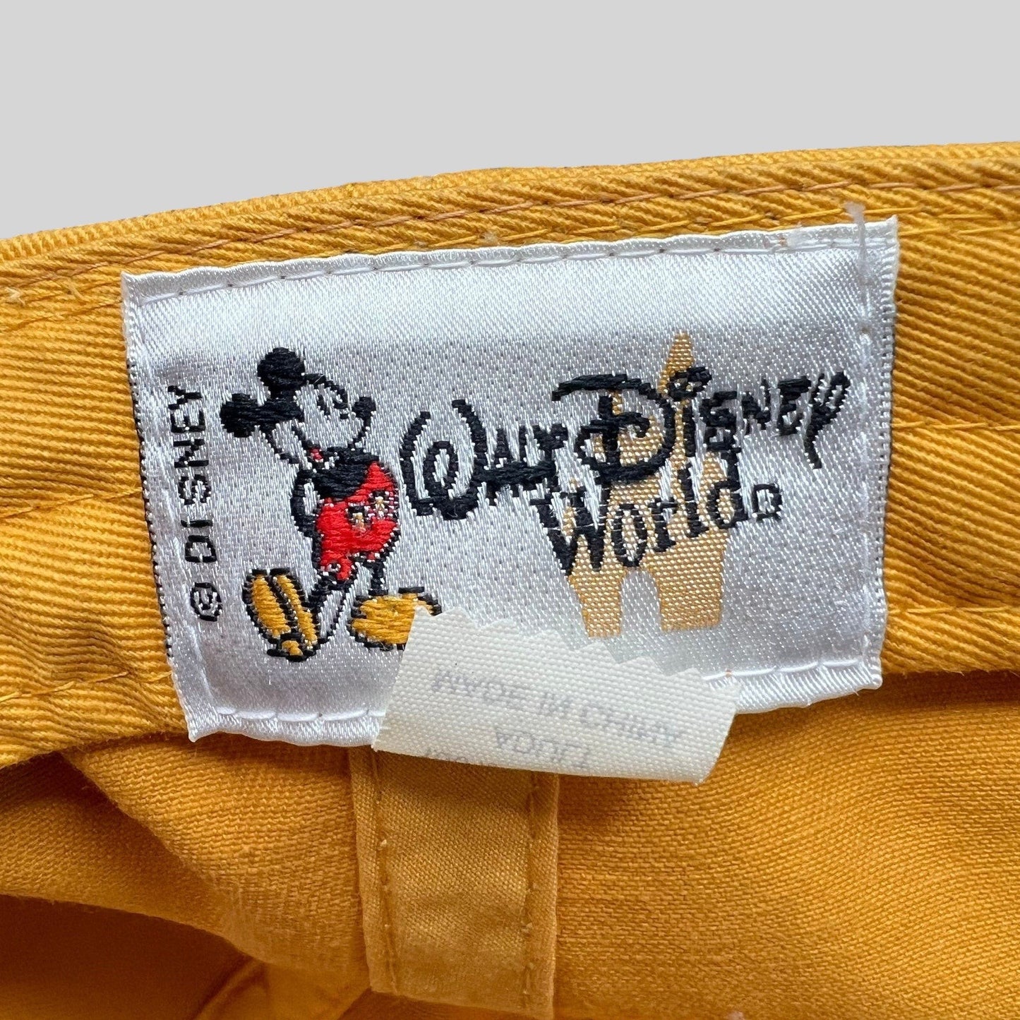 Raree Finds vintage Walt Disney World hat interior tag with Mickey Mouse graphic on yellow cotton fabric