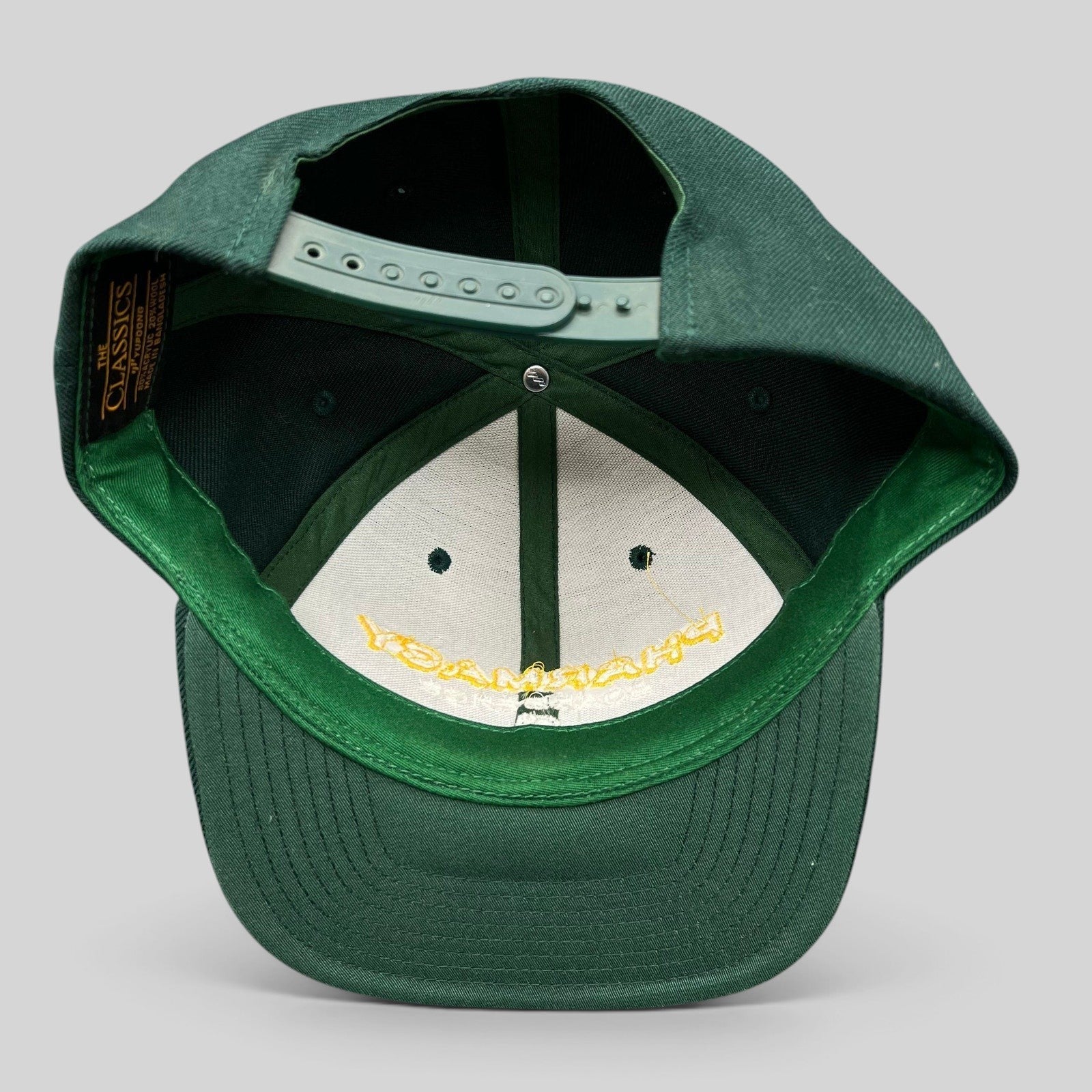 Raree Finds vintage forest green Yupoong Classics snapback hat showing interior construction and plastic strap