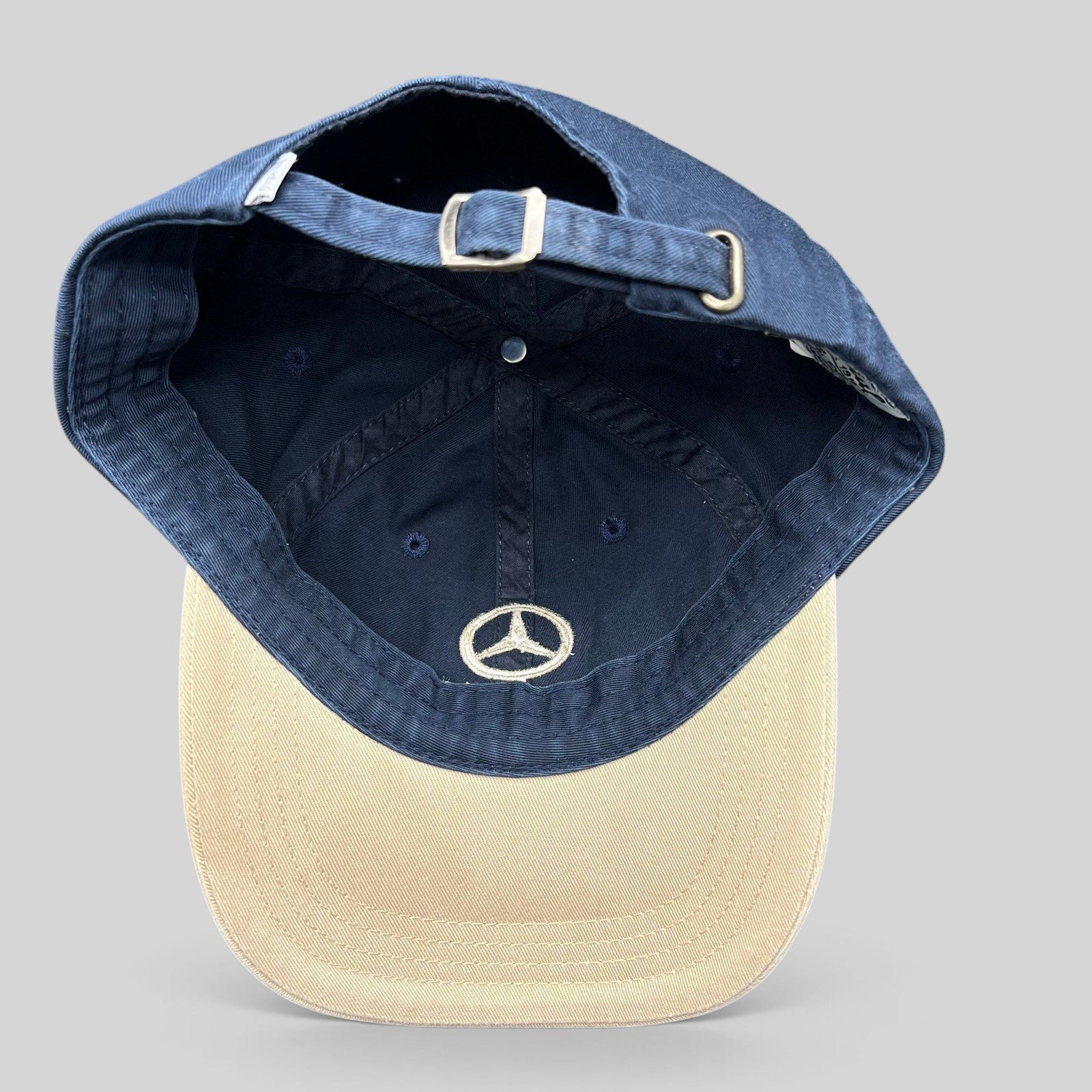 Raree Finds vintage Mercedes-Benz golf strapback hat with navy cotton crown, tan brim, and adjustable metal buckle.