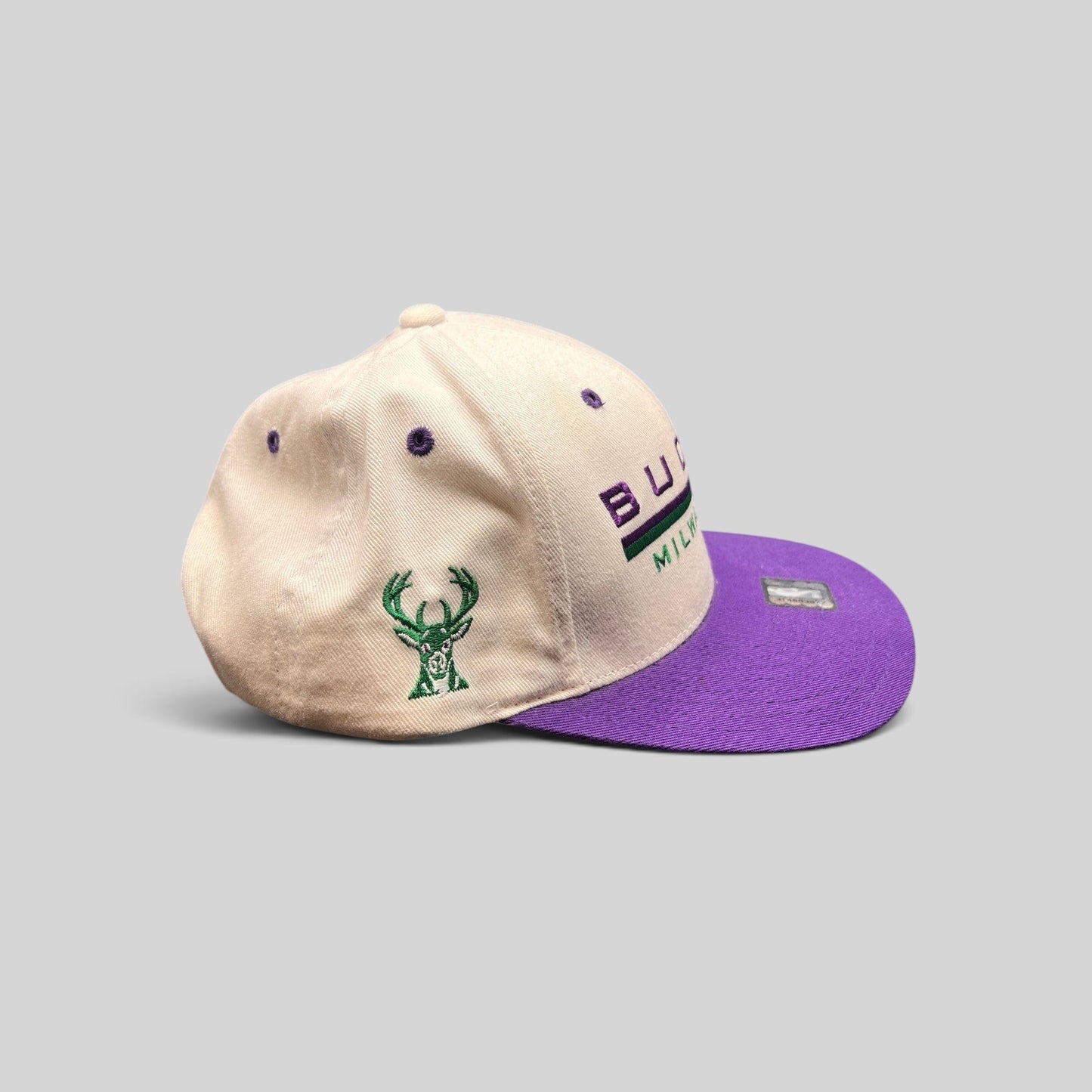 Raree Finds vintage 1990s Milwaukee Bucks snapback hat with white crown, purple brim, and embroidered team logo.