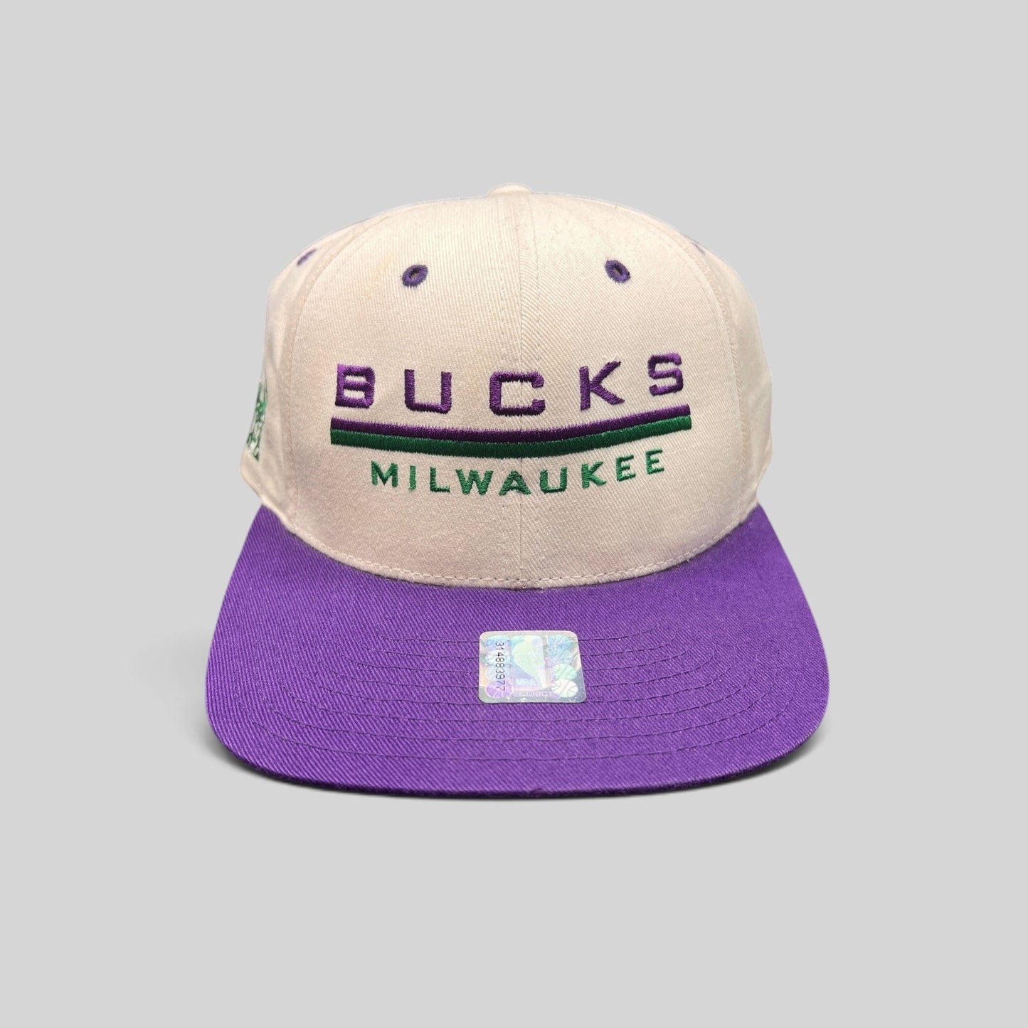 Raree Finds vintage 1990s Milwaukee Bucks snapback hat with white crown, purple brim, and embroidered team logo.