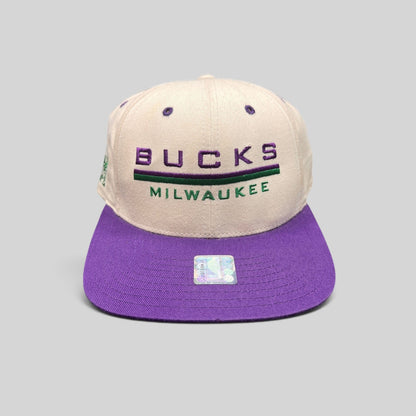 Raree Finds vintage 1990s Milwaukee Bucks snapback hat with white crown, purple brim, and embroidered team logo.
