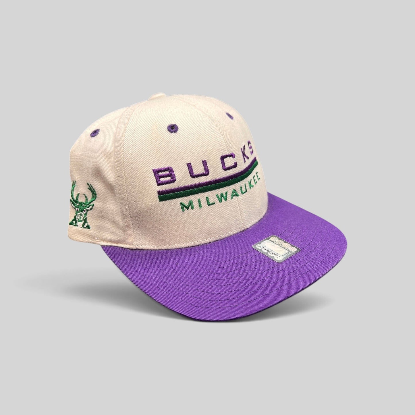 Raree Finds vintage 1990s Milwaukee Bucks snapback hat with white crown, purple brim, and embroidered team logo.