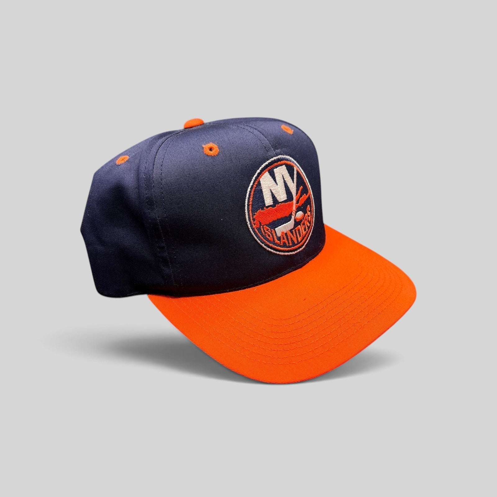 Raree Finds vintage 1990s New York Islanders snapback hat in navy and orange with embroidered team logo and green brim.