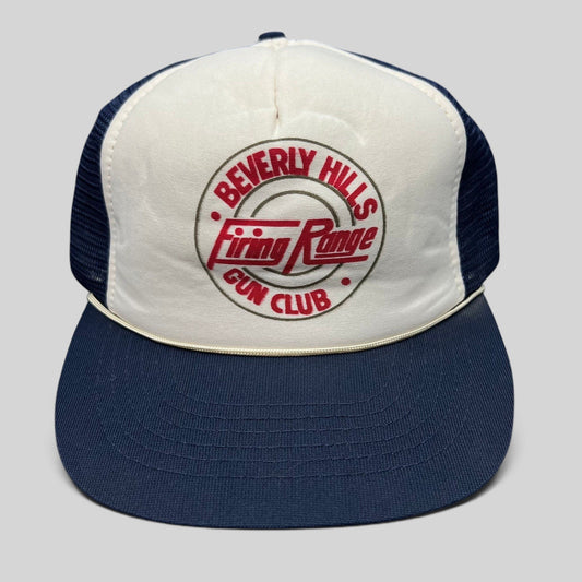 Raree Finds vintage Beverly Hills Gun Club trucker hat with white foam front, navy mesh, and red Firing Range graphic