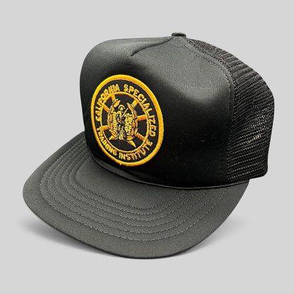 Raree Finds vintage black foam trucker hat with a gold embroidered California Specialized Training Institute patch.