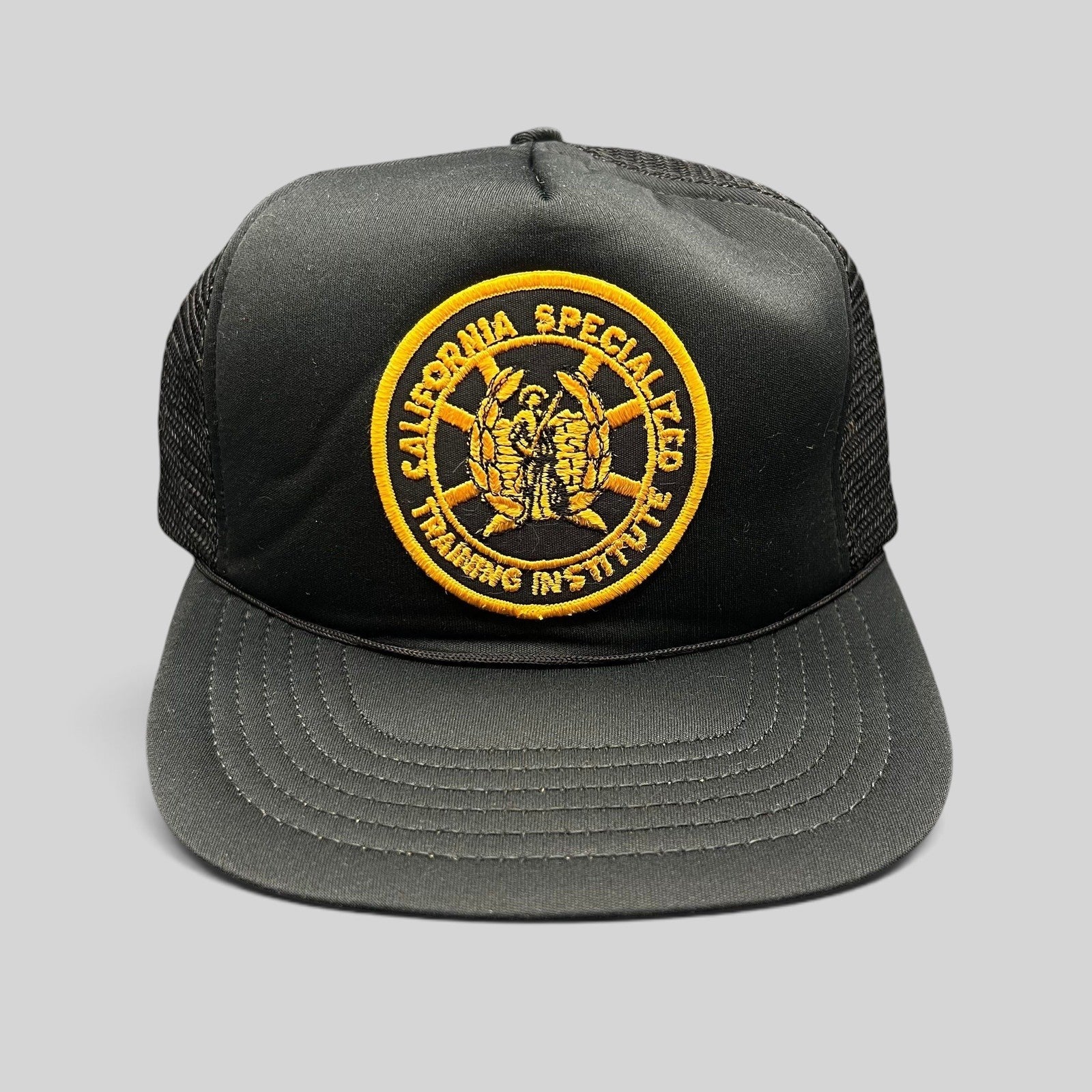 Raree Finds vintage black foam trucker hat with a gold California Specialized Training Institute embroidered patch.
