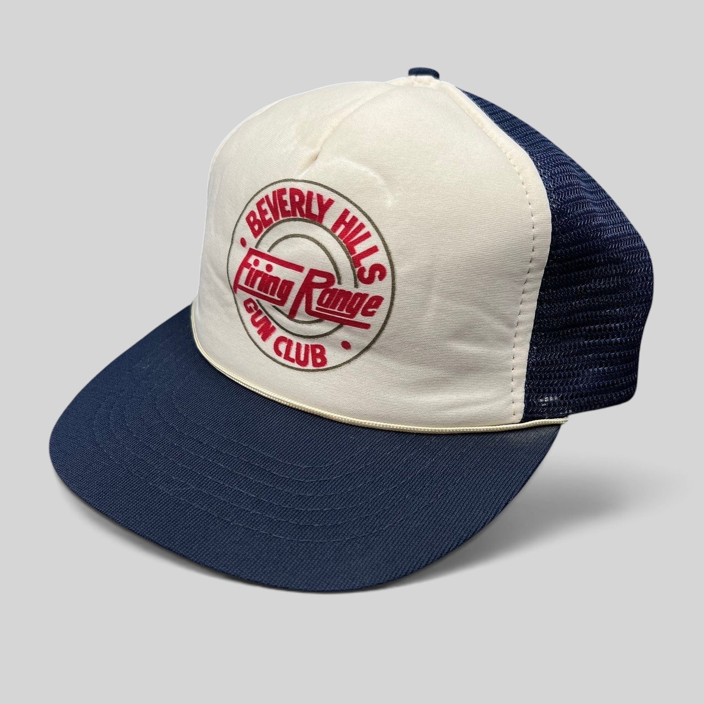 Raree Finds vintage Beverly Hills Gun Club trucker hat with white foam front, navy mesh back, and red graphic print.
