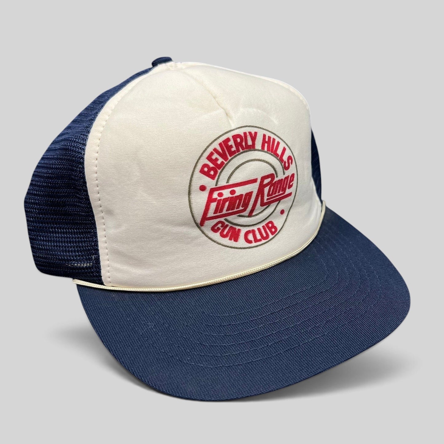 Raree Finds vintage Beverly Hills Gun Club trucker hat with white foam front, navy mesh back, and red graphic print.