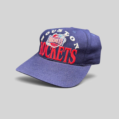 Raree Finds vintage 1990s Houston Rockets snapback hat in navy blue with red embroidered logo and green undervisor.