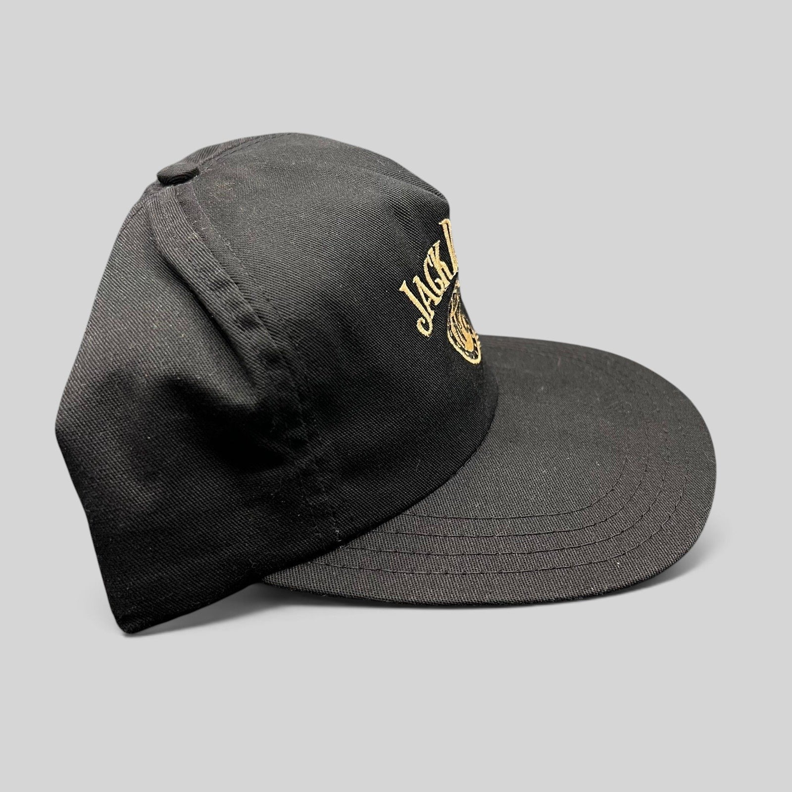 Raree Finds vintage 90s black Jack Daniel’s snapback hat with gold embroidered Old No. 7 logo on a six-panel crown.