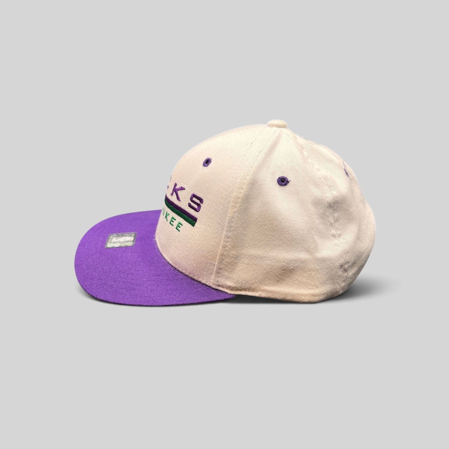 Raree Finds vintage 1990s Milwaukee Bucks snapback hat with a white crown, purple brim, and embroidered team logo.