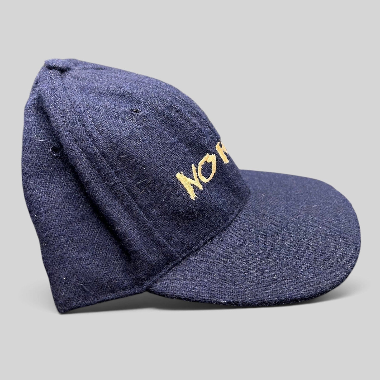 Raree Finds vintage 90s navy wool-blend snapback hat with gold No Fear Gear embroidery and structured six-panel design.