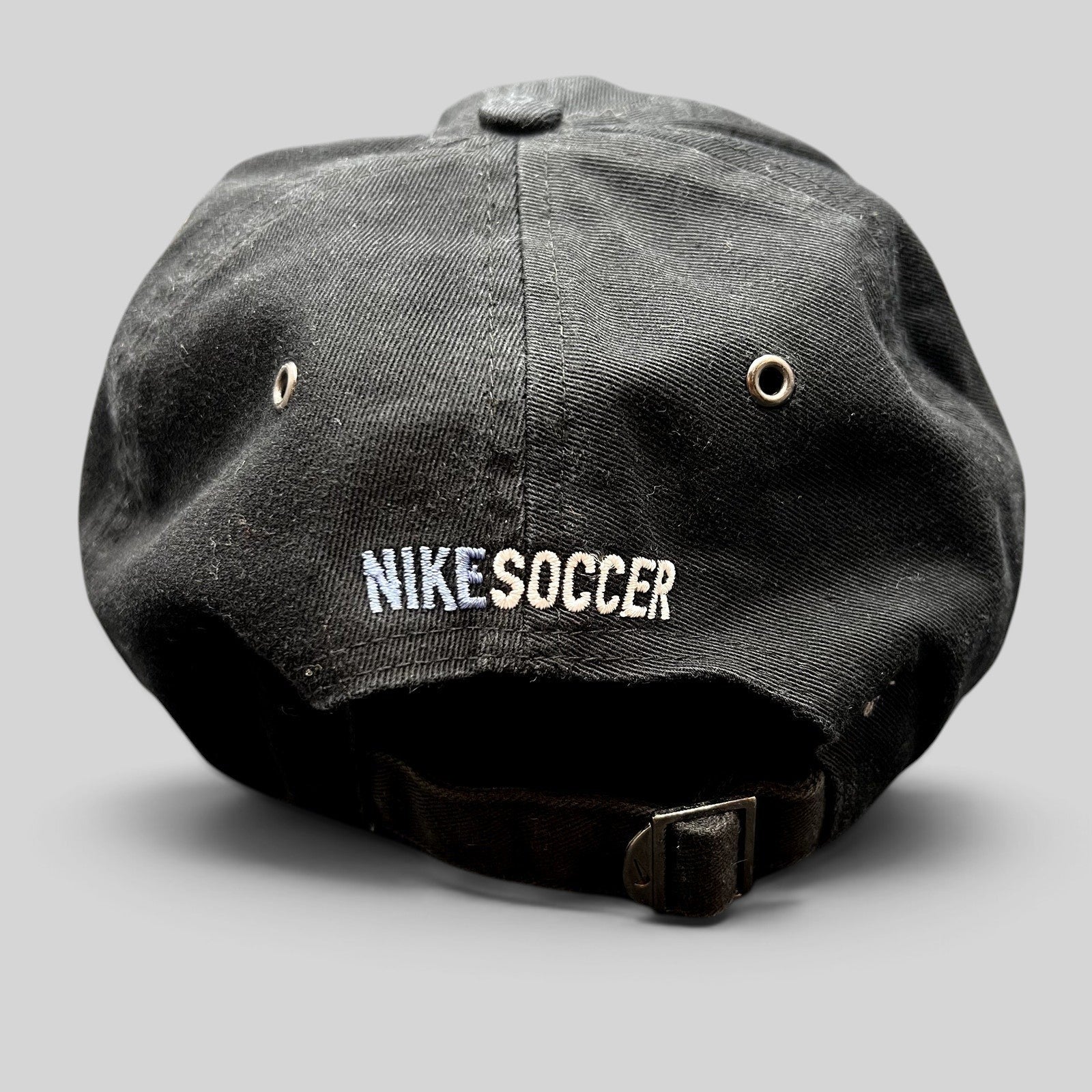 Raree Finds vintage black Nike Soccer strapback hat with embroidered logo and adjustable metal buckle back closure.