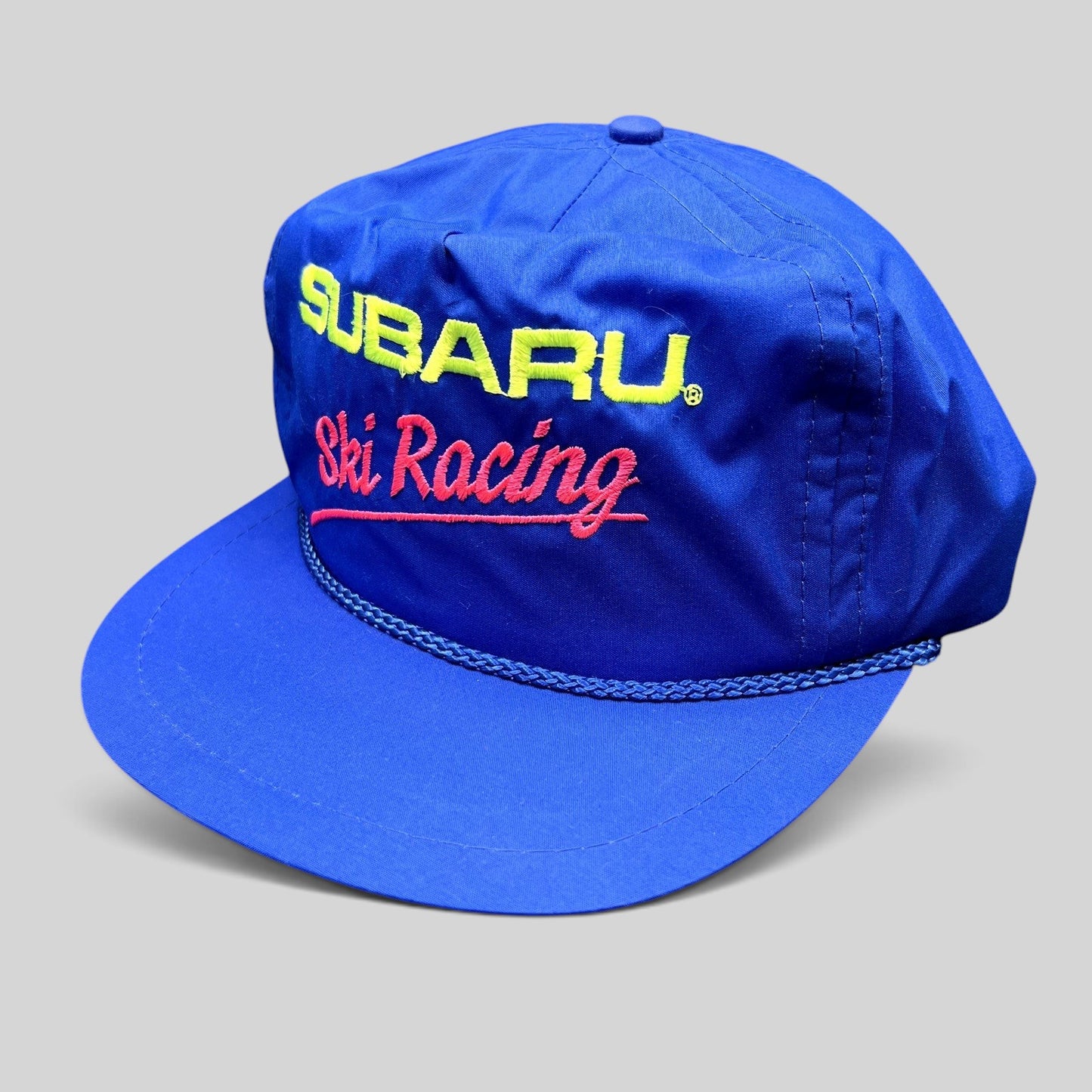 Raree Finds vintage blue nylon Subaru Ski Racing strapback hat with neon embroidery and front rope detail.