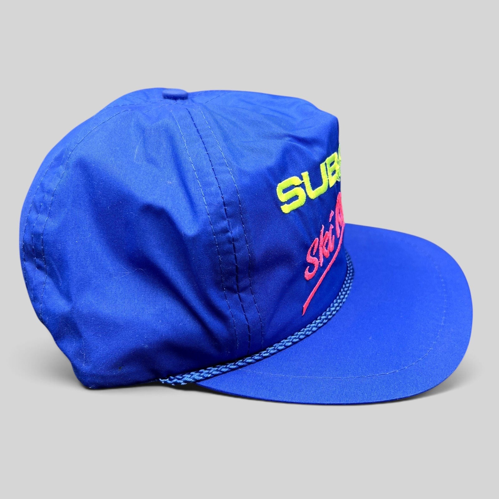 Raree Finds vintage blue nylon Subaru Ski Racing strapback hat with neon embroidery and rope detail.