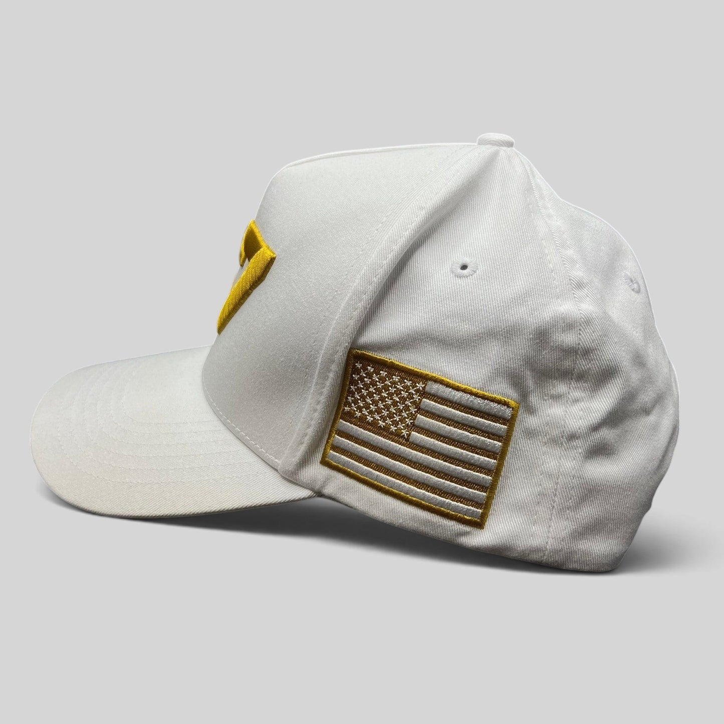 Raree Finds white cotton snapback hat featuring a gold embroidered American flag patch on the side panel.