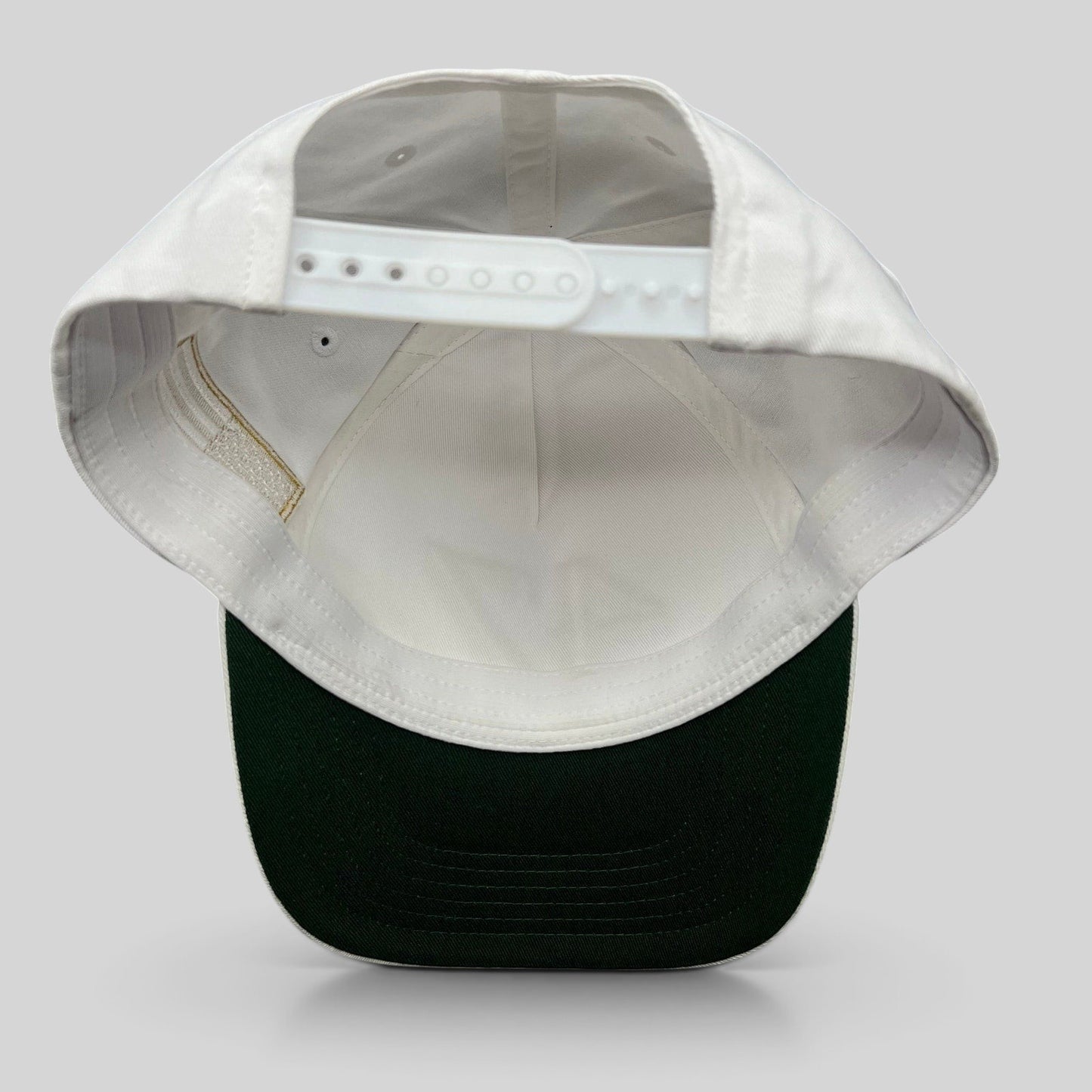 Raree Finds white cotton snapback hat with a green undervisor and adjustable plastic snap closure, back view.